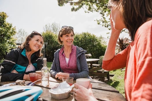 Three women are enjoying refreshments at a cafe together after a difficult bike ride.