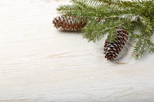 Light wooden background with fir branches and cones. New Year and Christmas