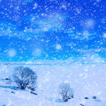 Snow covered empty frozen landscape of mountainside over blue sky with clouds