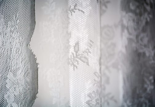 White curtain decorated with sewed floral pattern in lace. Interior shot with natural soft light