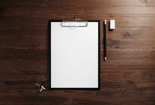 Clipboard with blank letterhead, pencil and eraser on wooden background. Responsive design template. Flat lay.