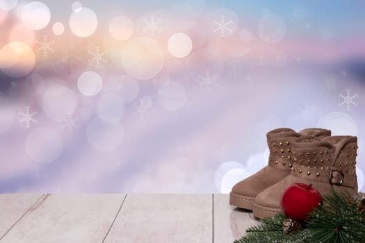 Christmas background. Table top christmas winter decoration background with an pair of winter boots and xmas tree fir branches and an red apple over beautiful abstract purple christmas background. Space for design. Card concept.