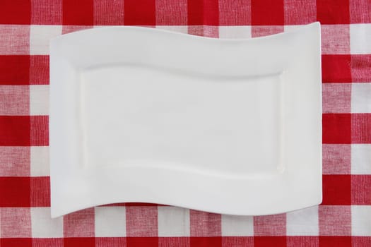 Empty white plate on red napkin or tablecloth. Top view. Template for your food and product display montage. Concept food. Copy space.
