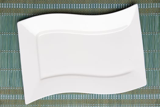 Empty white plate on green napkin or tablecloth. Top view. Template for your food and product display montage. Concept food. Copy space.