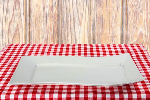 Empty white plate on red napkin over wooden background. For your food and product display montage. Concept food. Copy space.