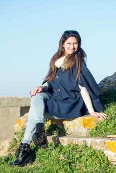 Beautiful happy young girl posing outdoors amongst ruins in beautiful light