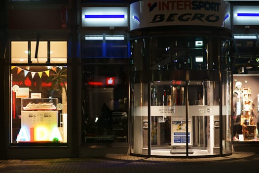 Limburg, Germany - November 03, 2018: Modern shop windows and a glass revolving door of an Intersport sports shop at night on November 03, 2018 in Limburg..