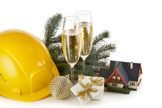 Construction hard hat, fir tree branches, model house, two glasses with champange and Christmas ornament isolated on a white background. New Year and Christmas. Horizontal view