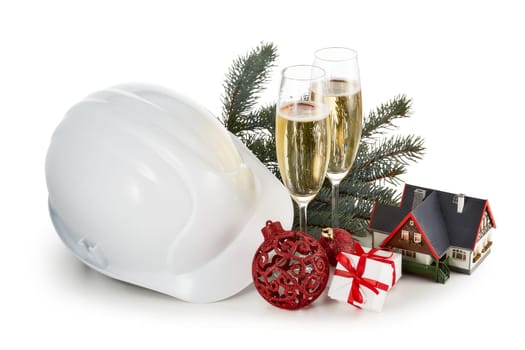 Construction hard hat, fir tree branches, model house, two glasses with champange and Christmas ornament isolated on a white background. New Year and Christmas. Horizontal view