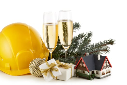 Construction hard hat, fir tree branches, model house, two glasses with champange and Christmas ornament isolated on a white background. New Year and Christmas. Horizontal view