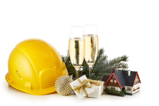 Construction hard hat, fir tree branches, model house, two glasses with champange and Christmas ornament isolated on a white background. New Year and Christmas. Horizontal view