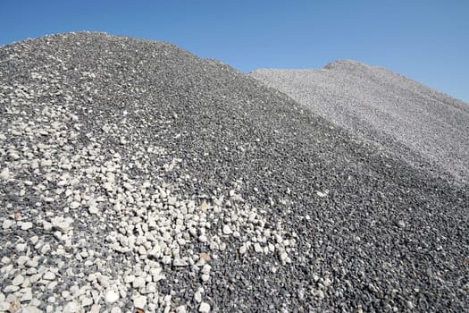 Large mound of crushed stone granite against the blue sky