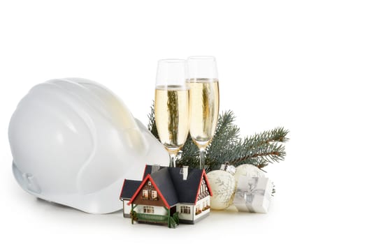 Construction hard hat, fir tree branches, model house, two glasses with champange and Christmas ornament isolated on a white background. Horizontal view with clipping path. New Year and Christmas.