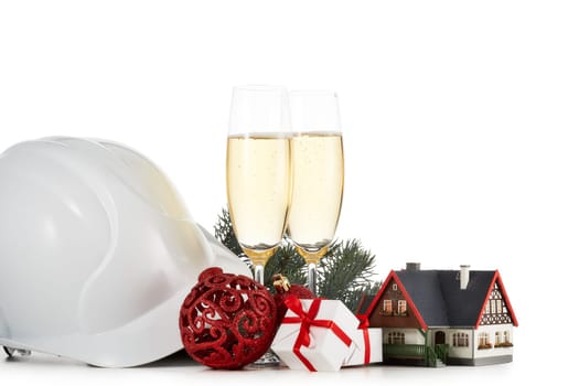 Construction hard hat, fir tree branches, model house, two glasses with champange and Christmas ornament isolated on a white background. New Year and Christmas. Horizontal view with copy space