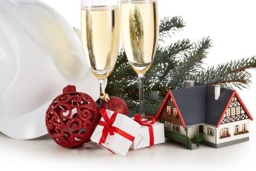 Construction hard hat, fir tree branches, model house, two glasses with champange and Christmas ornament isolated on a white background. New Year and Christmas. Horizontal view