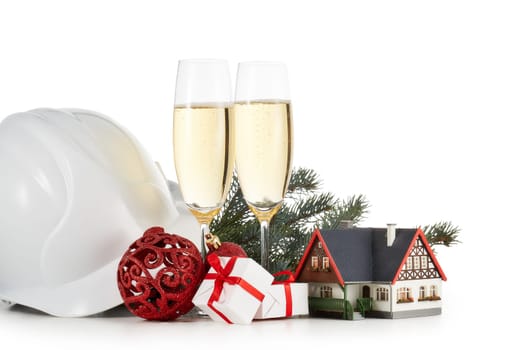 Construction hard hat, fir tree branches, model house, two glasses with champange and Christmas ornament isolated on a white background. New Year and Christmas. Horizontal view with copy space