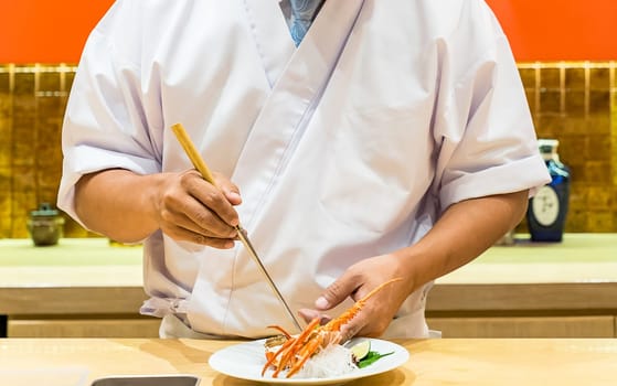 Chef preparing and cooking lobster sashimi