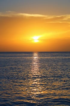 Colorful empty seascape with shiny sea over cloudy sky and sun during sunset in Cozumel, Mexico