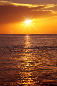 Colorful empty seascape with shiny sea over cloudy sky and sun during sunset in Cozumel, Mexico