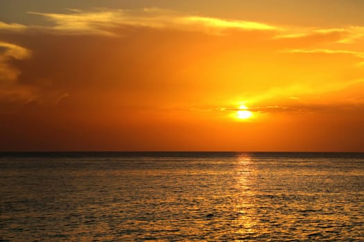 Colorful empty seascape with shiny sea over cloudy sky and sun during sunset in Cozumel, Mexico