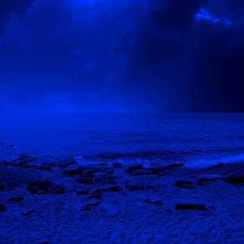seascape image of sandy and rocky beach over stormy sky