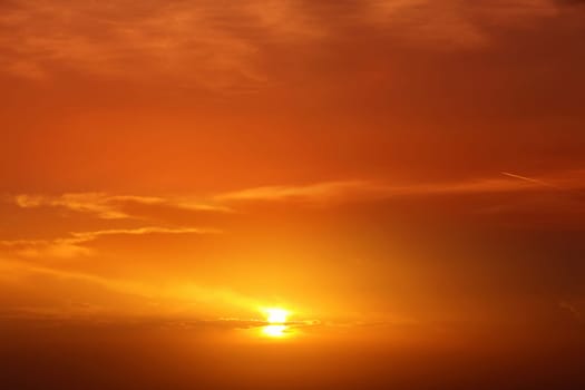 Beautiful cloudscape of orange colored sunset sky with shining sun