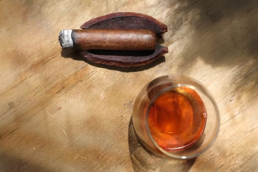 elevated view of close up cigar and drink on wooden table