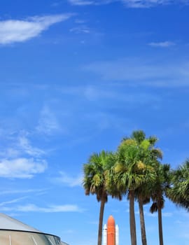 Kennedy space center entrance with space rocket and palm trees over blue sky in Florida, USA