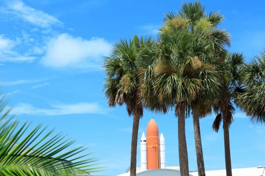 Kennedy space center entrance with space rocket and palm trees over blue sky in Florida, USA