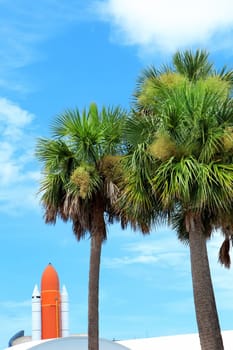 Kennedy space center entrance with space rocket and palm trees over blue sky in Florida, USA
