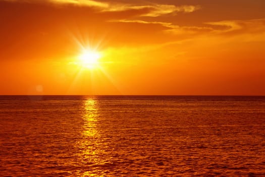 Colorful empty seascape with shiny sea over cloudy sky and sun during sunset in Cozumel, Mexico