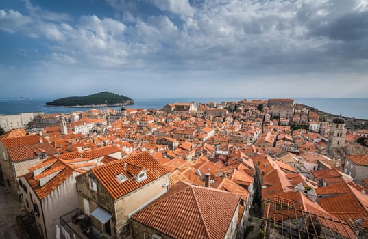Rooftops of old houses in Dubrovnik, viewed from the Old Town fortified walls with Lokrum Island in the background
