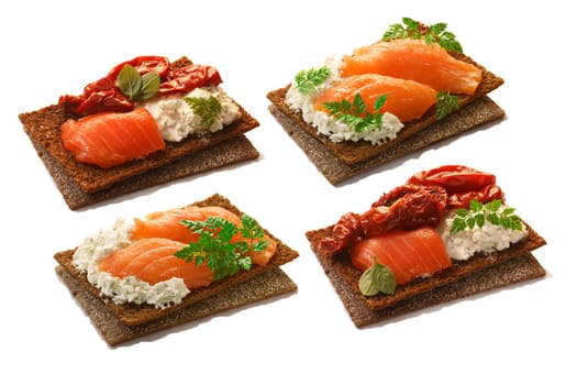Set of bread crisps (crispbread open-faced sandwiches) with salmon, soft cream cheese, sun dried tomatoes and fresh chervil. Clipping paths for each crisp and for shadows, infinite depth of field