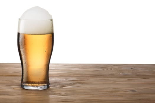 Moist glass of light beer with foam on either wooden table or bar counter. Clipping pahts for both glass and background, infinite depth of field. Mockup, template