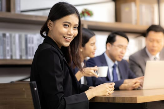 Portrait of confidence Businesswoman sit at table in meeting room in cafe with business team in background using for coporate background work