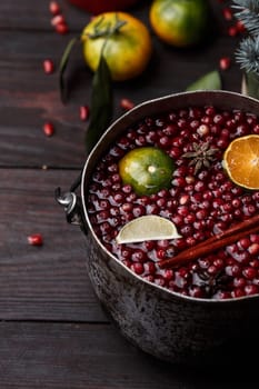 Cranberry mandarin pomegranate punch or mulled wine in a rustic aged pot near blue spruce branch