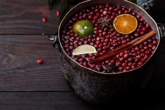 Cranberry mandarin pomegranate punch or mulled wine in a rustic aged pot near blue spruce branch