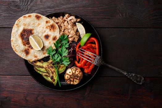 Fajita with pulled pork and bell peppers. Tortillas, grilled avocado, onions  served with meat and vegetables on plate. Tex-mex cuisine