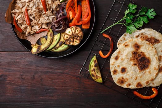 Fajita with pulled pork and bell peppers. Tortillas, grilled avocado, onions  served with meat and vegetables on plate. Tex-mex cuisine
