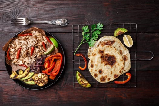 Fajita with pulled pork and bell peppers. Tortillas, grilled avocado, onions  served with meat and vegetables on plate. Tex-mex cuisine