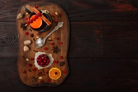 Cranberry citrus punch or mulled wine with ingredients over dark wooden table.
