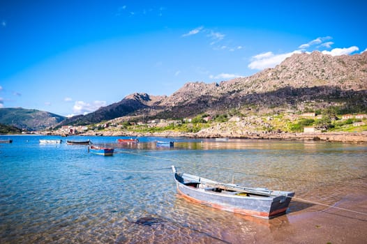 Beauty Atlantic coast with fishing boats, beach, ocean, village, mountains and sky with clouds. Galicia, Spain.
