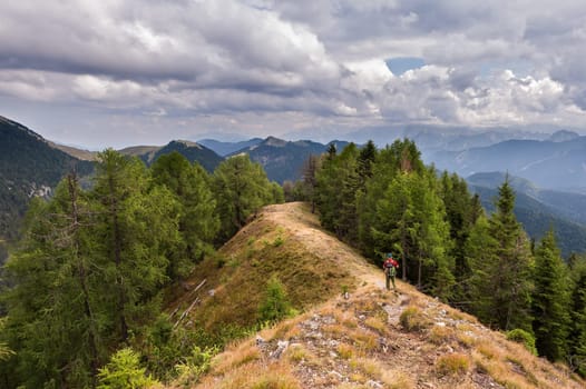 Hiker walks on the mountain ridge under a stormy sky