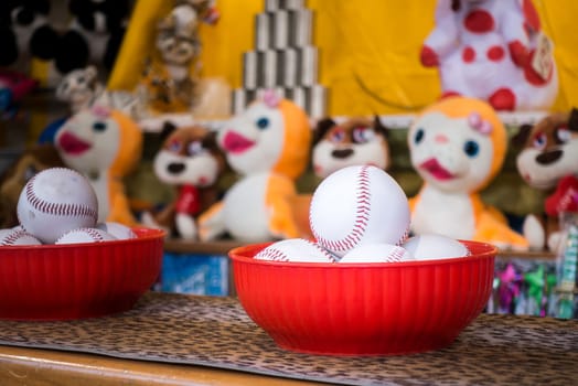 Close-up of baseball balls for the game of throw at jars in a fair. In the background the jars and the prize puppets