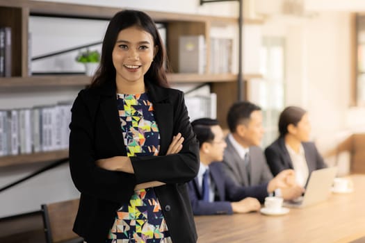 Portrait of confidence Businesswoman stand in front of table in meeting room in cafe with business team in background using for coporate background work