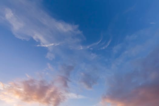 Great wispy clouds and blue sky background. Early morning sunlight with pink colours
