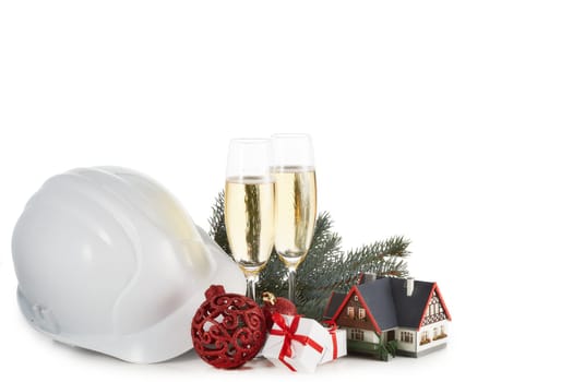 Construction hard hat, fir tree branches, model house, two glasses with champange and Christmas ornament isolated on a white background. New Year and Christmas. Horizontal view with copy space