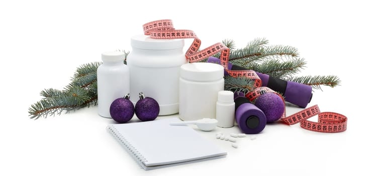 Sports nutrition (supplements), dumbbells, fir tree branches and christmas ormament on a white background. Horizontal view. New Year and Christmas. Fitness. Healthy lifestyle.