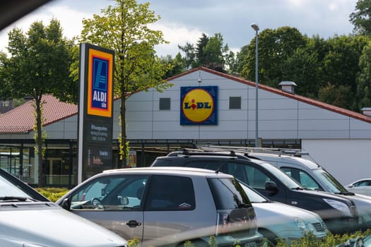 Mülheim Ruhr, Nrw, Germany - June 04, 201k7:Aldi and Lidl supermarket parking lot in Muelheim in Mülheim, Ruhr area, view over the street. A car drives to a parking lot. Outside the supermarket are people.