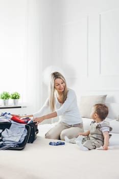 Travelling with kids. Happy mother with her child packing clothes for their holiday